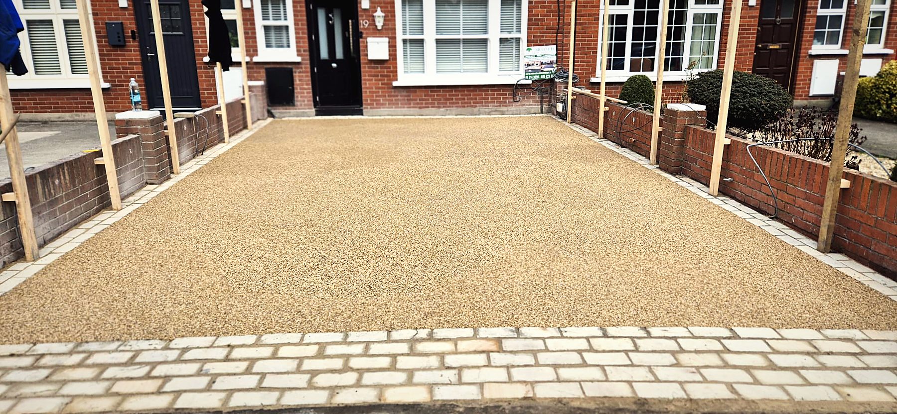 Golden resin-bound driveway with cobble border in front of a terraced home